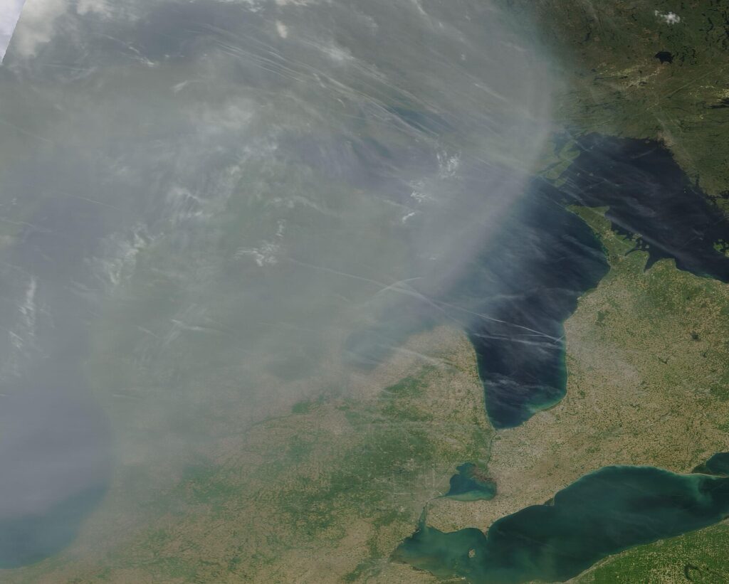 Satellite view of a gray haze of wildfire smoke drifting over Michigan and the Great Lakes